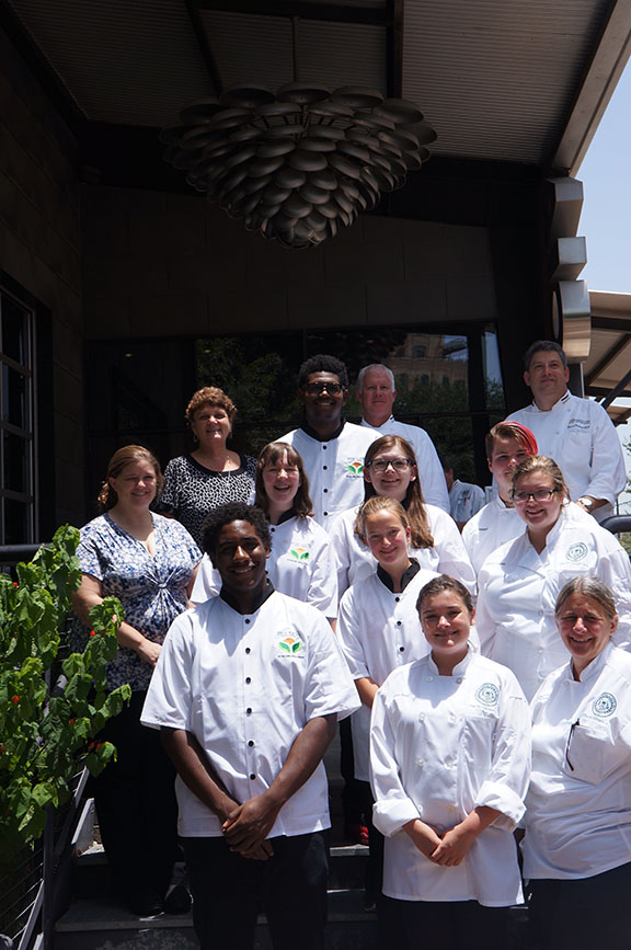 Contestants posing for a photo wearing Pulses chef aprons.